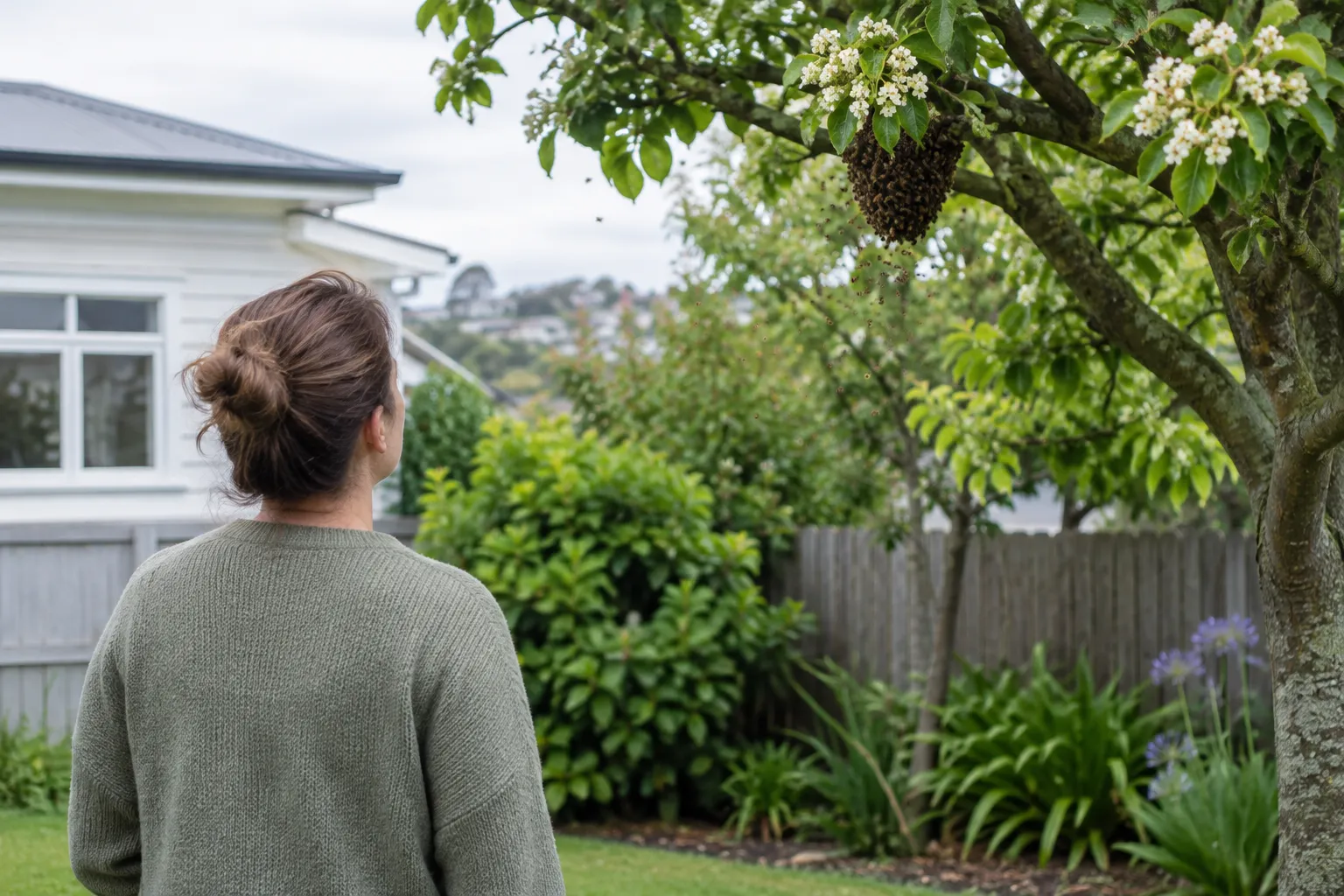 A person seen from behind watching bees around a tree branch from a safe distance in their garden